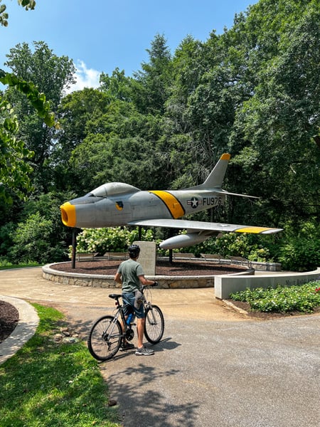 Male biker in front of F 86 Sabre plane memorial at Cleveland Park in Greenville